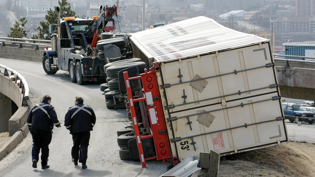 A flipped semi-truck being pulled upright by a tow truck after an Oklahoma highway accident